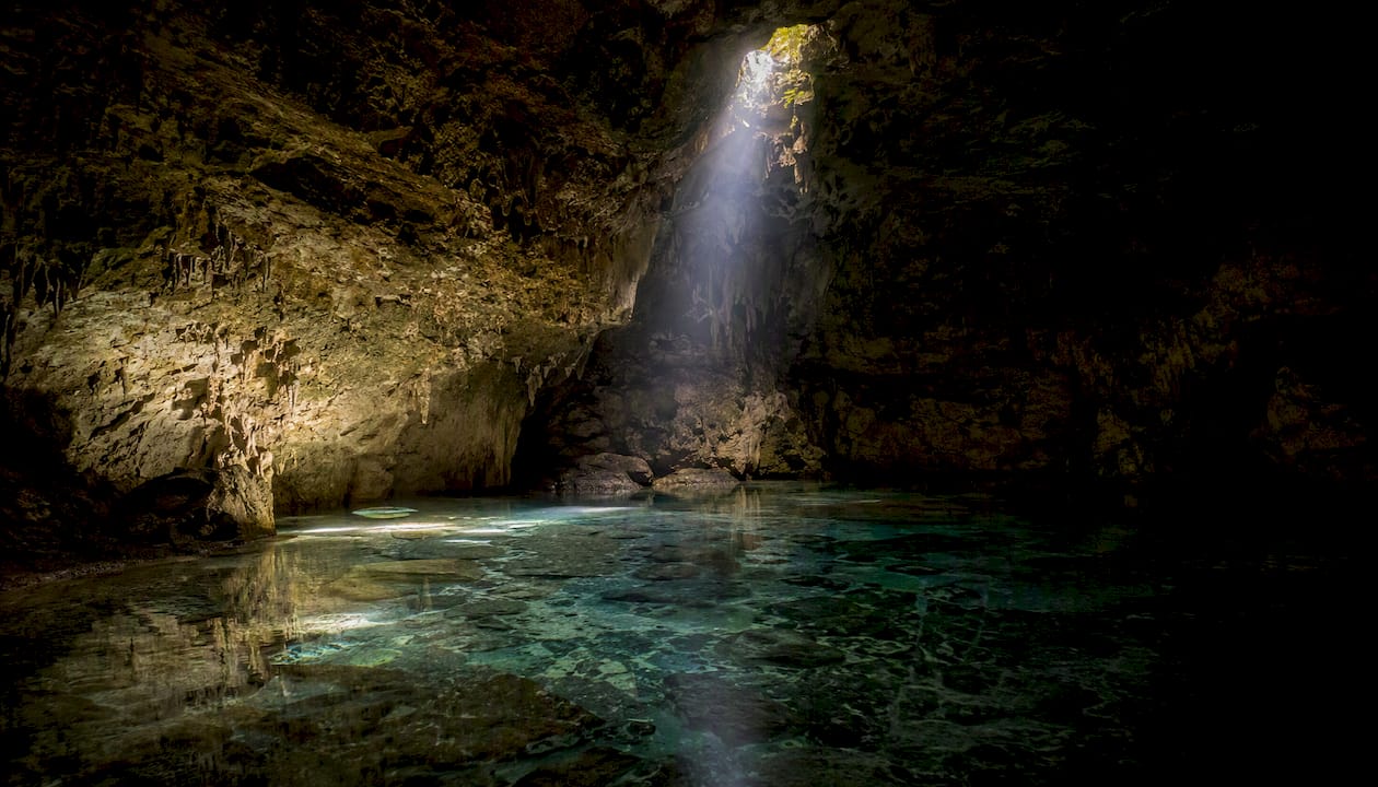 Dimly lit cavern cenote interior with headlamp beam
